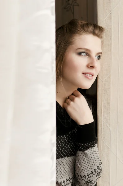 Pretty Woman peeping from behind the curtain — Stock Photo, Image