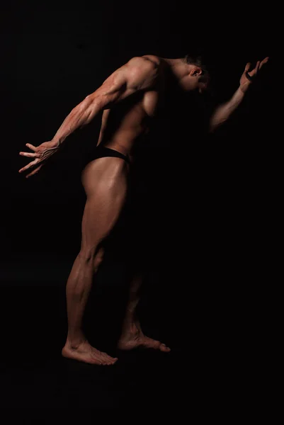 Young attractive man in a black bathing suit bodybuilder — Stock Photo, Image