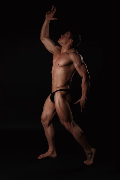 Giovane uomo attraente in un costume da bagno nero bodybuilder — Foto Stock