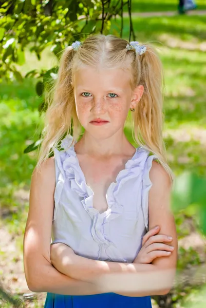 Blonde girl standing in a garden with hands clasped, looking int — Stock Photo, Image