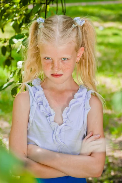 Blonde girl standing in the garden with hands clasped, looking o — Stock Photo, Image