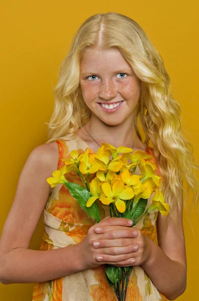 Chica rubia de pie en un jardín con las manos apretadas, mirando — Foto de Stock