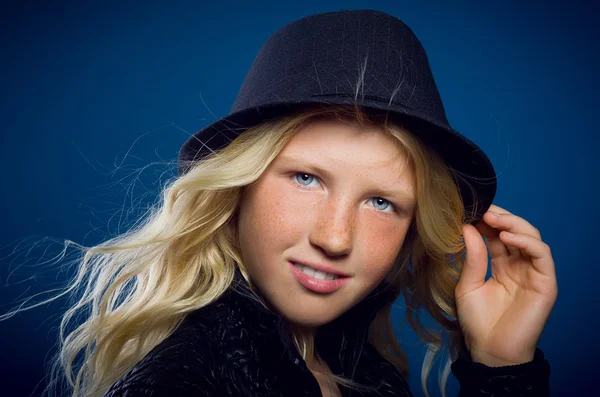 Girl smiling holding on to the hat and looking at the camera — Stock Photo, Image