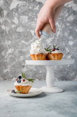 Gri bir fotoğrafta yaban mersini ve biberiye kremalı kek (kek). Yüksek anahtarlı, ev yapımı pişirilmiş mallar.