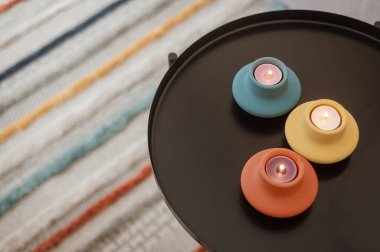 Siyah kahve masasında mumlar olan çok renkli şamdanlar. İskandinav tarzı, rahat ev, dekor elementleri, hyuge