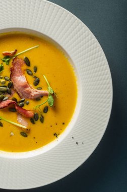 Bezelye tohumlu pastırmalı balkabağı çorbası ve güzel beyaz bir tabakta filizler. Basit, sağlıklı besleyici yiyecekler. Ev yapımı yemekler bir restoranda servis edilir.