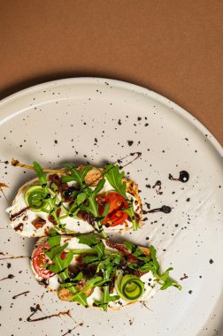 Domatesli bruschetta, yumuşak peynir, roka ve kahverengi arka planda güneşte kurutulmuş domates. Bir gurme için hafif bir atıştırmalık. İtalyan mutfağı