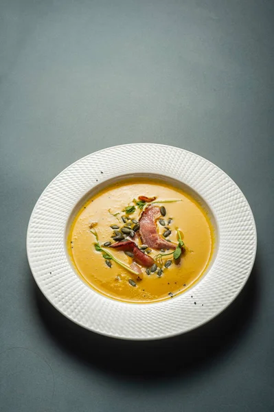 美しい白いプレートにエンドウ豆の種ともやしとベーコンとカボチャのスープ シンプルな健康的な栄養価の高い食品 レストランで提供される自家製の食事 — ストック写真