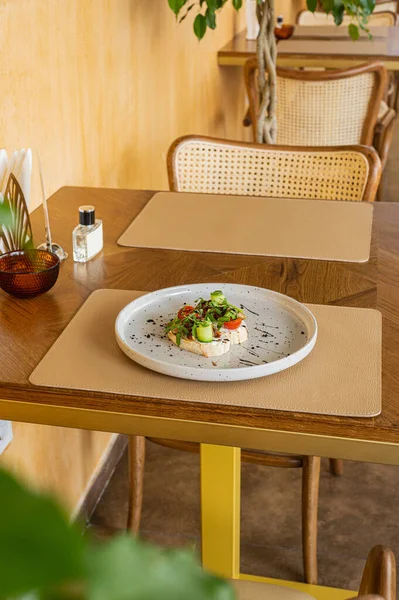 Sıcak ahşap bir masada domates, yumuşak peynir, roka ve güneşte kurutulmuş domatesle iştah açıcı bruschetta. Bir gurme için hafif bir atıştırmalık. İtalyan mutfağı