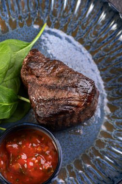 Ispanaklı ızgarada ızgara biftek ve parlak mavi bir tabakta sos. Yürekli bir gurme yemeği. Basit geleneksel yemek, öğle yemeği fikri. Restoran malzemeleri..