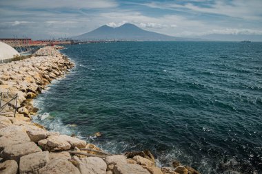 Sakin mavi Tyrhenian Denizi. Napoli 'nin setinden Vezüv Dağı yanardağına bakın. Deniz boyunca taştan dalgalı su kıvrımları