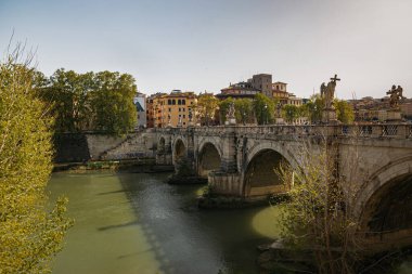 Tiber Nehri ve köprünün güzel manzarası. Sahil boyunca uzanan yeşil levhalar güneşten korur. İlkbaharda Roma 'da güzel bir yürüyüş..