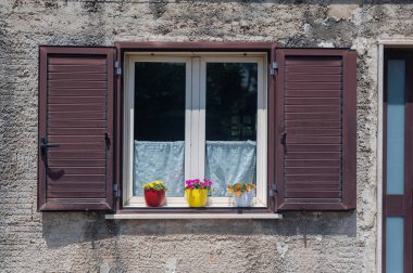 Güney İtalya 'da eski bir ortaçağ evinde çiçekli güzel bir pencere. Ev konforu ve uyum. Kahverengi ahşap çerçeve.
