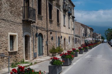 Güney İtalya 'da ortaçağ caddesi. Paestum şehri. Kırmızı sardunyaları olan güneşli güzel bir cadde.