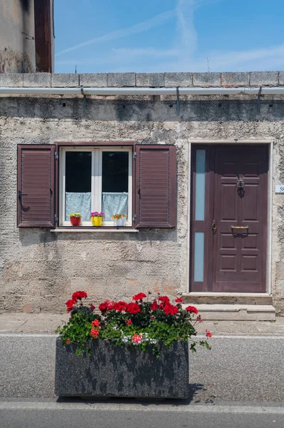 南イタリアの古い中世の家の花と美しい窓 家庭の快適さと調和 茶色の木枠 花壇の赤いゼラニウム — ストック写真