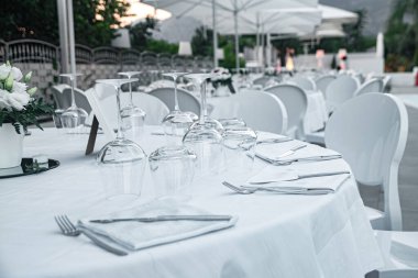 Set table with white tablecloth in restaurant. A round table in a restaurant on a summer terrace under the open sky at sunrise