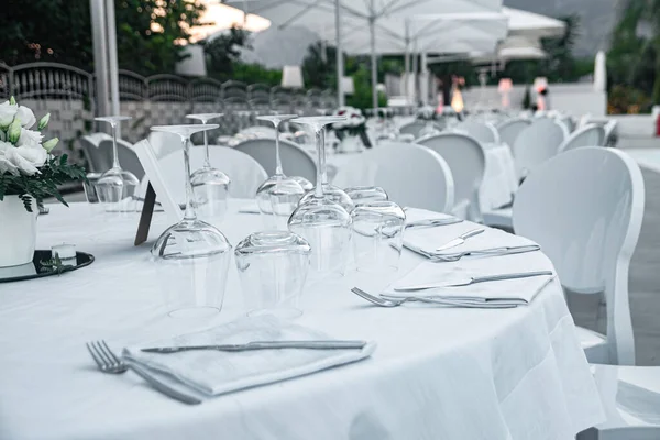 Set table with white tablecloth in restaurant. A round table in a restaurant on a summer terrace under the open sky at sunrise