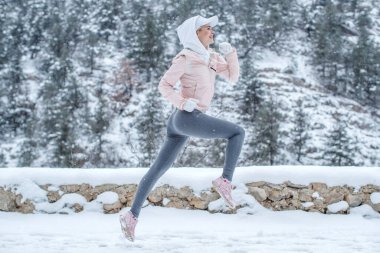 Kadın spora gidiyor. Kız kışın koşar.
