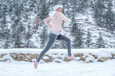 Kadın spora gidiyor. Kız kışın koşar.