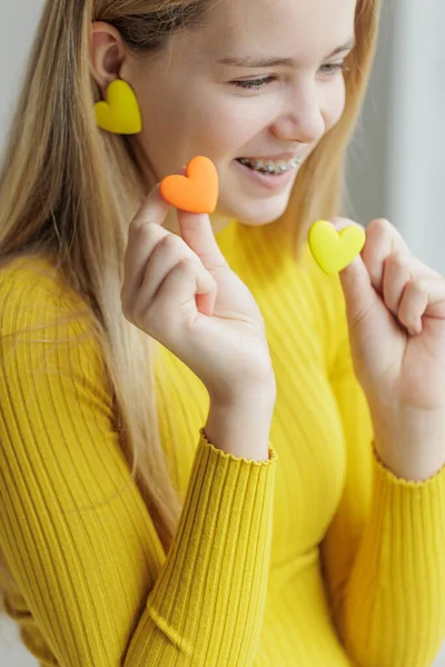 Teenage girl chooses jewelry earrings. Heart shaped earrings. St. Valentines Day. — Stock Photo, Image