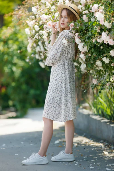 Mooi meisje in rozen in de natuur. Jonge vrouw met bloemen. — Stockfoto