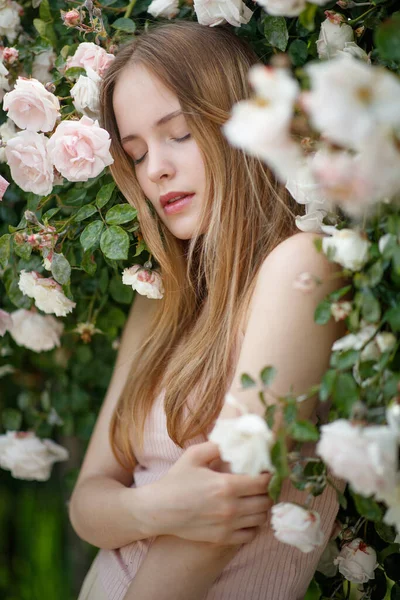 Mooi meisje in rozen in de natuur. Jonge vrouw met bloemen. — Stockfoto