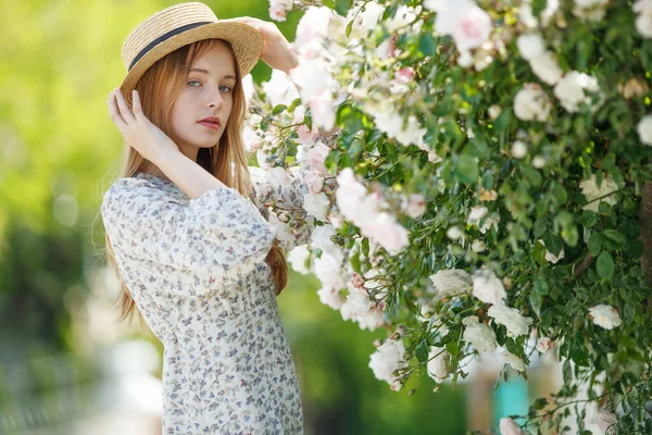 Beautiful girl in roses in nature. Young woman with flowers. — Stockfoto