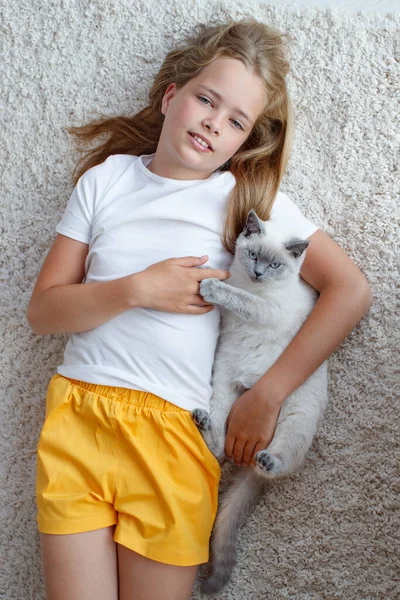 Un niño con un animal. Chica con un gato en casa. — Foto de Stock