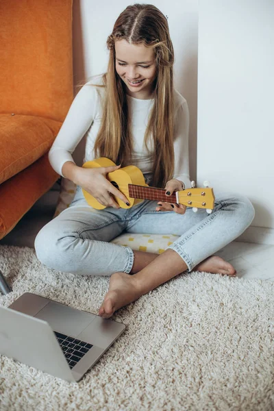 A teenage girl is learning to play the guitar, ukulele. — стоковое фото