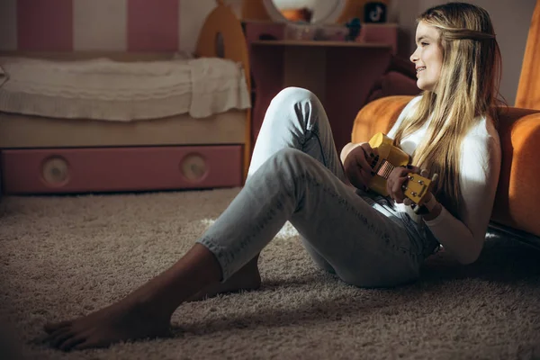 A teenage girl is learning to play the guitar, ukulele. — Fotografie, imagine de stoc