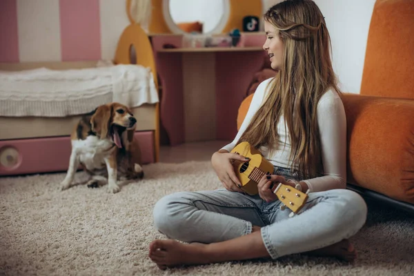 A teenage girl is learning to play the guitar, ukulele. — Foto de Stock