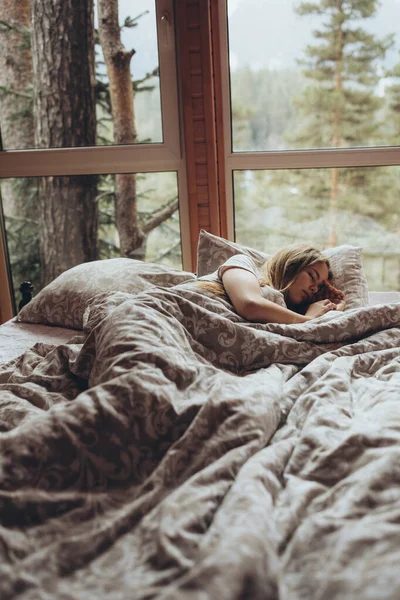Девушка спит на кровати. Молодая и красивая девушка спит с прекрасным видом из окна. — стоковое фото