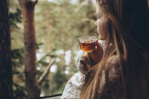 Красива дівчина п'є чай вдома з видом на природу . — стокове фото