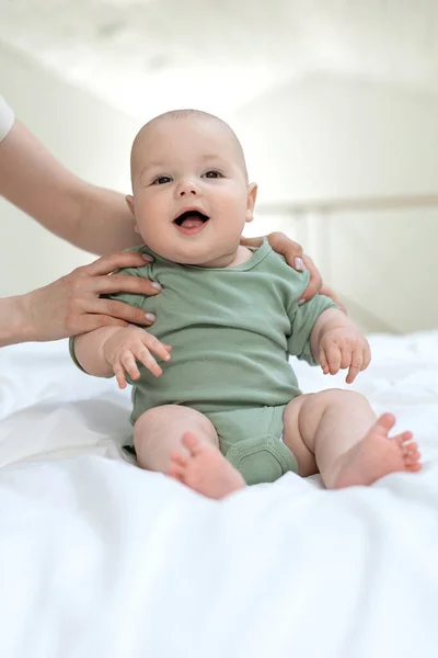 El bebé aprende a sentarse. Mamá enseña a un niño pequeño a sentarse. —  Fotos de Stock