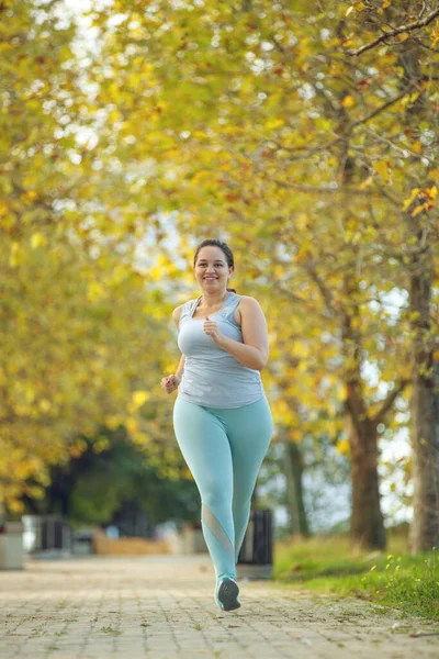 An attractive plus size woman in a sports top and leggings, goes