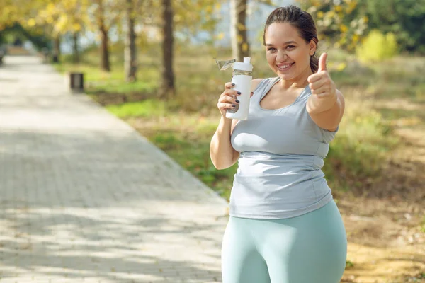An attractive plus size woman in a sports top and leggings, goes