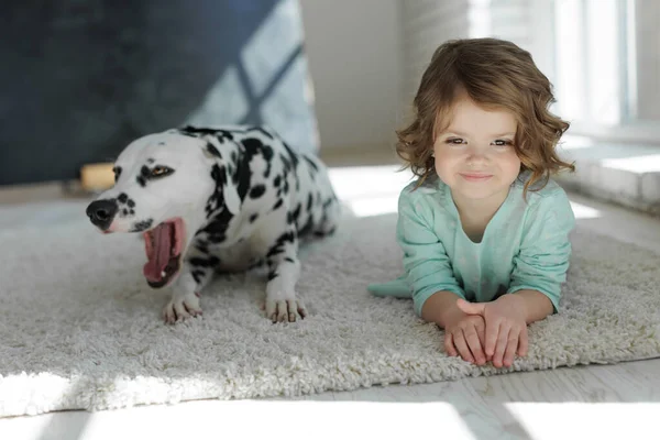 Köpekli bir çocuk. Mutlu bir kız Dalmaçyalı bir köpekle halıda yatıyor..