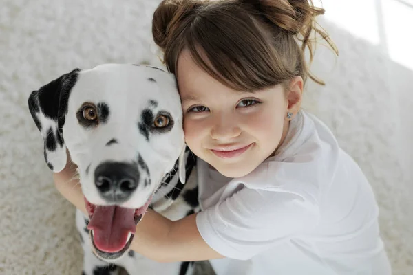 Ребенок с собакой. Счастливая девушка лежит на ковре с далматинской собакой. — стоковое фото