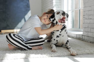 Köpekli bir çocuk. Mutlu bir kız Dalmaçyalı bir köpekle halıda yatıyor..