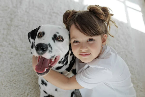 Ребенок с собакой. Счастливая девушка лежит на ковре с далматинской собакой. — стоковое фото
