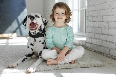 Köpekli bir çocuk. Mutlu bir kız Dalmaçyalı bir köpekle halıda yatıyor..