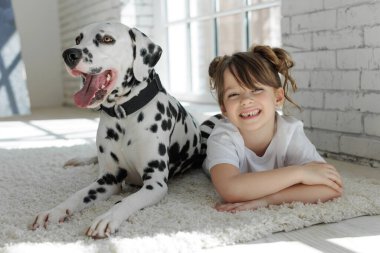 Köpekli bir çocuk. Mutlu bir kız Dalmaçyalı bir köpekle halıda yatıyor..