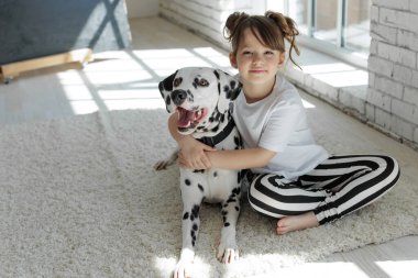 Köpekli bir çocuk. Mutlu bir kız Dalmaçyalı bir köpekle halıda yatıyor..