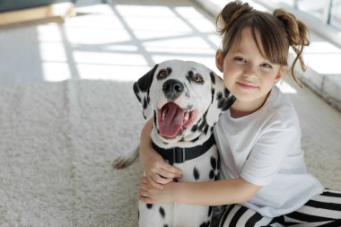 Köpekli bir çocuk. Mutlu bir kız Dalmaçyalı bir köpekle halıda yatıyor..