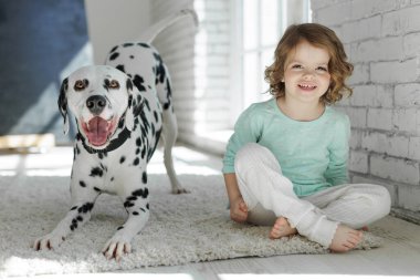 Köpekli bir çocuk. Mutlu bir kız Dalmaçyalı bir köpekle halıda yatıyor..