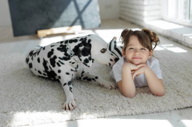 Köpekli bir çocuk. Mutlu bir kız Dalmaçyalı bir köpekle halıda yatıyor..