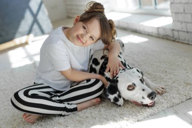 Köpekli bir çocuk. Mutlu bir kız Dalmaçyalı bir köpekle halıda yatıyor..