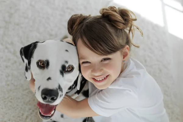 Barn med hund. En lykkelig jente ligger på et teppe med en dalmatiner.. – stockfoto