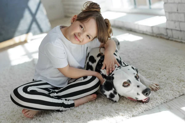 Köpekli bir çocuk. Mutlu bir kız Dalmaçyalı bir köpekle halıda yatıyor..