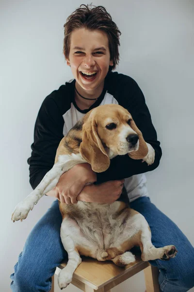 Portrét pohledného teenagera se pózujícím pózujícím psem na bílém pozadí. Studio focení. Dítě se psem. — Stock fotografie